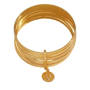Close-up detail of multi-layer gold bangles featuring vintage coin relief pendant