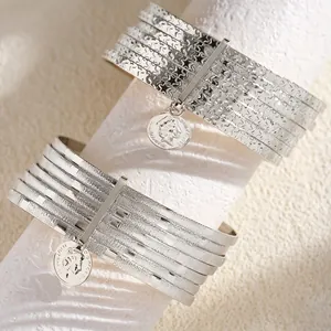 Detailed view of silver-toned multi-layered bangles with textured stars and coin pendants.