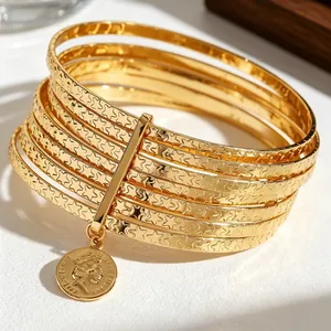 Close-up of gold star-patterned stacked bangles with Queen Elizabeth II coin charm.