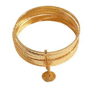 Close-up of vintage gold layered bangles with hammered star texture and coin pendant