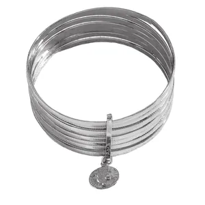 Macro view of multi-layered silver bangles with a vintage queen coin pendant charm