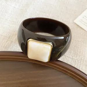 Brazalete de acrílico marrón estilo vintage con detalle de resina veteada cuadrada sobre bandeja