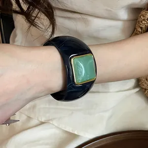 Detalle de un brazalete de acrílico azul marino con incrustación de resina verde.