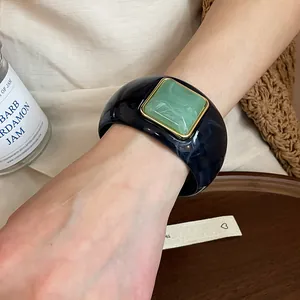 Primer plano detallado de un brazalete de acrílico jaspeado con gema verde cuadrada
