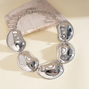 Detailweergave van een grove zilveren geplooide metalen statement ketting op steen