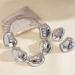 Macroweergave van glanzende zilverkleurige gekreukte metalen ketting en oorbellen set.