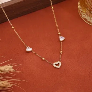 Primo piano di una collana a cuore dorata con strass su sfondo caldo terracotta.