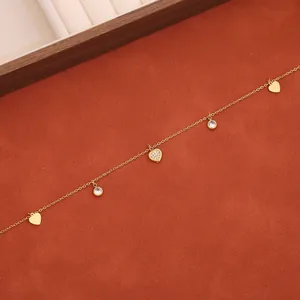 Dettaglio di una collana in acciaio inossidabile dorato con cuori e pendenti in zirconi.