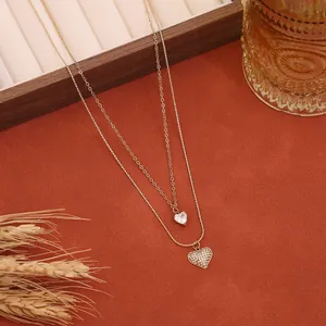 Vista dettagliata di una collana dorata a due strati con due pendenti a cuore in strass brillanti