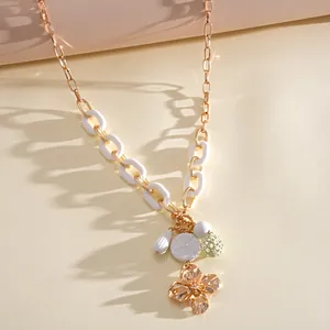 Gros plan détaillé des breloques fleur en acrylique et goutte d'eau sur collier doré