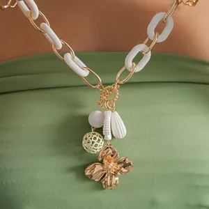 Vue détaillée montrant la chaîne en acrylique et le pendentif fleur de ce collier doré chic