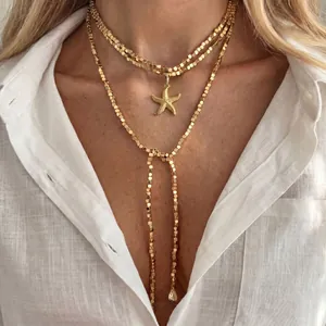 Collana a strati dorata con ciondolo a stella marina su camicia di lino bianca