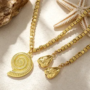 Dettaglio della collana di perline dorate con un ciondolo a conchiglia strutturato