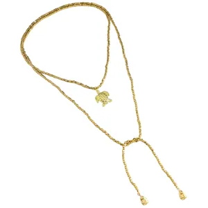 Dettaglio della collana di perline dorate con ciondolo a forma di tartaruga marina e gocce
