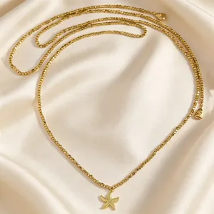 Dettaglio macro di una collana di perline dorate con ciondolo a forma di stella marina su seta