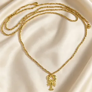Primo piano di un ciondolo a forma di aragosta dorata su una collana di perline
