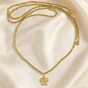 Dettaglio ravvicinato di collana di perle dorate con un ciondolo a forma di tartaruga marina
