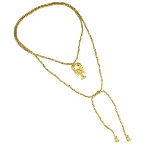 Primo piano di una collana di perline dorate con ciondolo a forma di aragosta e cubetti.