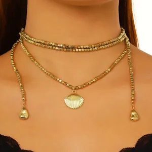 Dettaglio macro di una collana di perle dorate a strati con un ciondolo a conchiglia