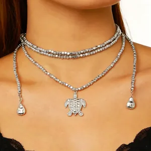 Primo piano di una collana a strati con perline argentate e un ciondolo a tartaruga.