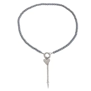 Vista dettagliata della collana di perle grigie con ciondoli a cuore e punta in argento.