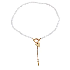 Dettaglio di una collana di perle bianche con pendente a cuore dorato e catenina.