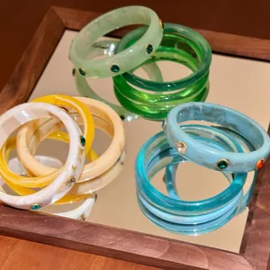 Dettaglio di bracciali in resina colorata con strass scintillanti su uno specchio