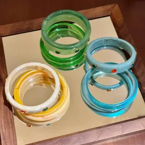 Vista dettagliata di bracciali in resina colorata con strass su una superficie specchiata