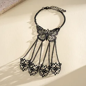 Detailed shot of a black hollow butterfly slave bracelet with four finger rings