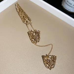Detailopname van gouden gotische holle conische vingerringen verbonden door kettingen
