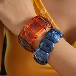 Close-up detail of retro acrylic marbled geometric bracelets on a model's wrist
