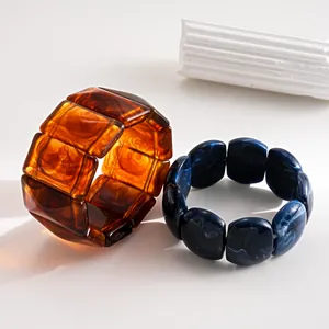 Close-up detail of retro acrylic bracelets featuring amber and navy blue marble patterns