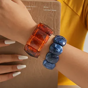 Detail view of vintage marbled acrylic chunky bracelets in amber and blue textures.
