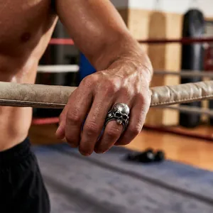 Close-up of a punk style skull ring with cracked texture on a male hand in a gym