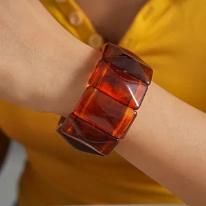 Detailed view of an amber acrylic rectangular link bracelet worn on the wrist