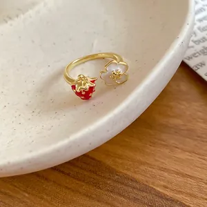 Primo piano di un grazioso anello regolabile con ciondoli a fragola e fiori bianchi