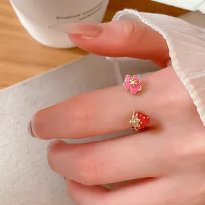 Dettaglio ravvicinato di un anello aperto con fragola e fiore sull'indice di una donna dolce
