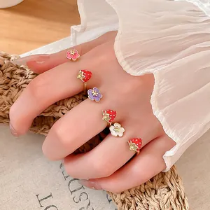 Primo piano dettagliato di anelli aperti in smalto fragola e fiori indossati sulla mano