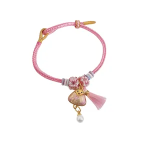 Handmade pink braided Dragon Boat Festival bracelet featuring a zongzi charm and pearl