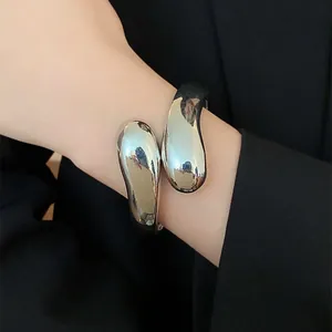 Primer plano detallado de un brazalete de gota de agua plateado en la muñeca de un modelo