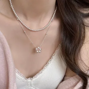 Collier élégant à double rangée de perles avec pendentif fleur porté par un mannequin.