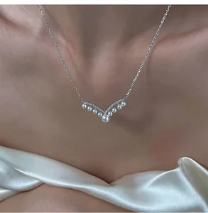 Detailed close-up of an elegant V-shaped pearl necklace worn against a soft silk background