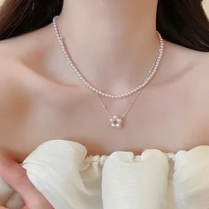 Elegant double-layered necklace with pearl beads and a floral pendant on a model.