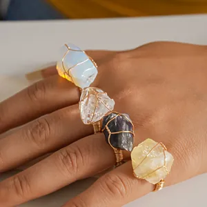 Detail view of handmade gold wire wrapped raw natural crystal rings on model hand