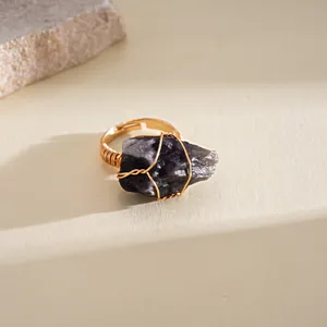 Detailed macro view of a handmade raw dark purple amethyst wire wrapped gold ring.