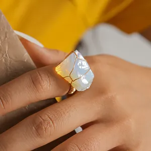 Macro view showing the intricate wire-wrapped detail on a natural raw opal crystal ring