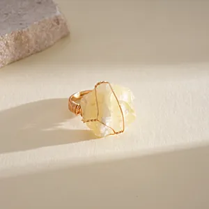 Close-up of a handmade gold wire-wrapped ring with a large yellow natural crystal stone.