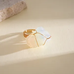 Detailed macro view of a handmade gold wire wrapped natural raw opal crystal ring