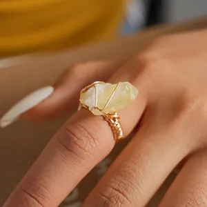Detailed close-up of a handmade gold wire-wrapped ring with natural raw yellow crystal