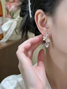 Sweet multi-color enamel flower drop earrings worn by a model in a close-up detail